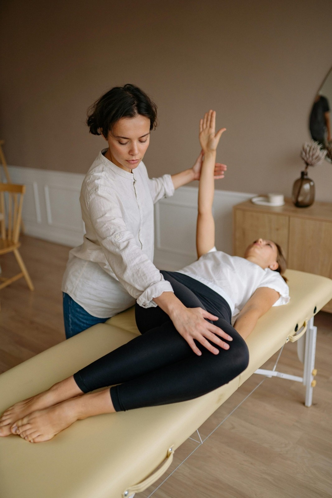Un physiothérapeute aide une femme à faire des exercices thérapeutiques à l'intérieur.